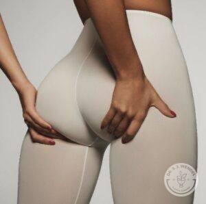 View of a woman wearing grey yoga pants grabbing her buttocks