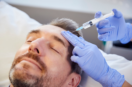 man with grey hair has eyes shut while receiving Botox treatment in forehead