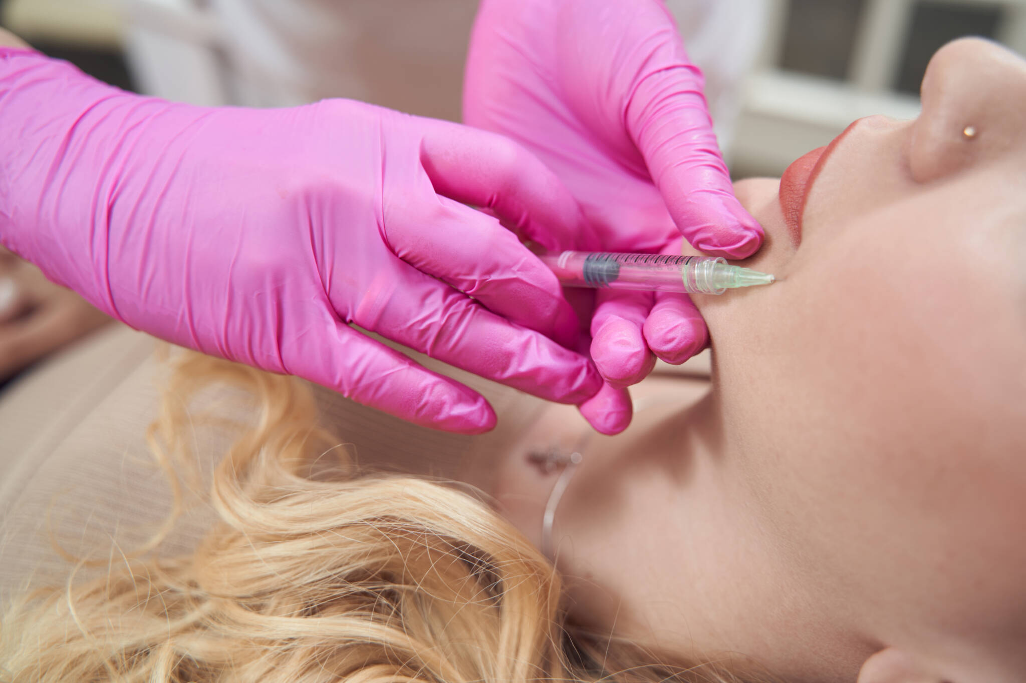 Cropped head side view portrait of unrecognized female client receiving cosmetic procedure into the chin in beauty salon