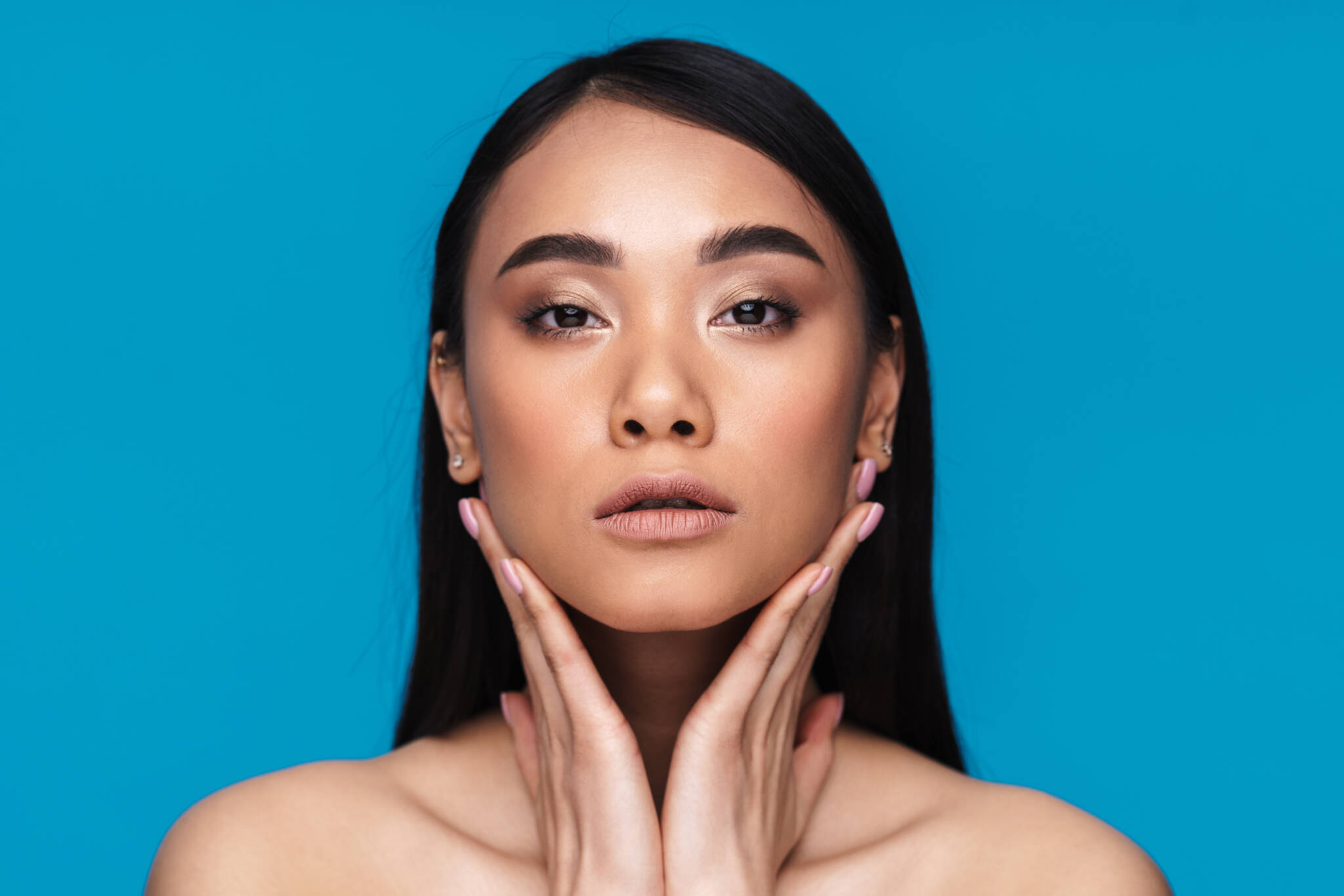 Photo of a beautiful young woman posing isolated over blue wall background.