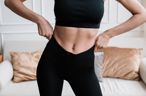 woman showing slim midriff while wearing a sports bra and yoga pants