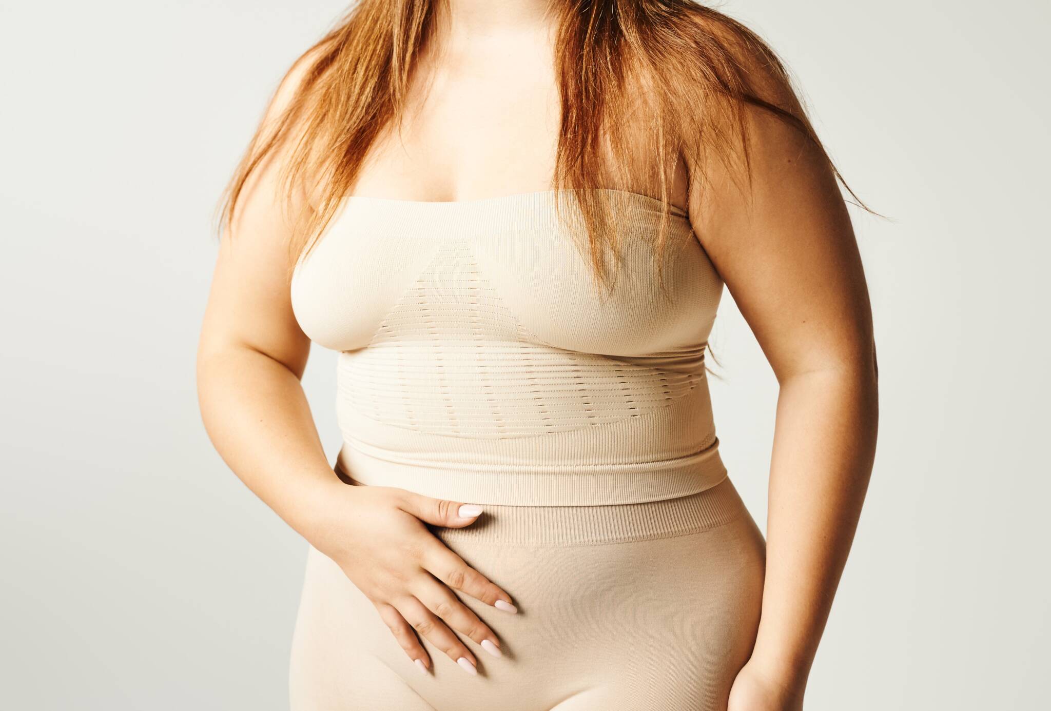 Plus size woman with long hair and bare shoulders in compression top and bottoms