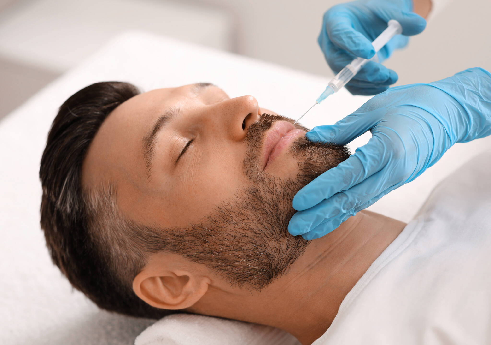 A male plastic surgery client receives an injectable treatment for smile lines. Injectables and fillers to treat aging skin