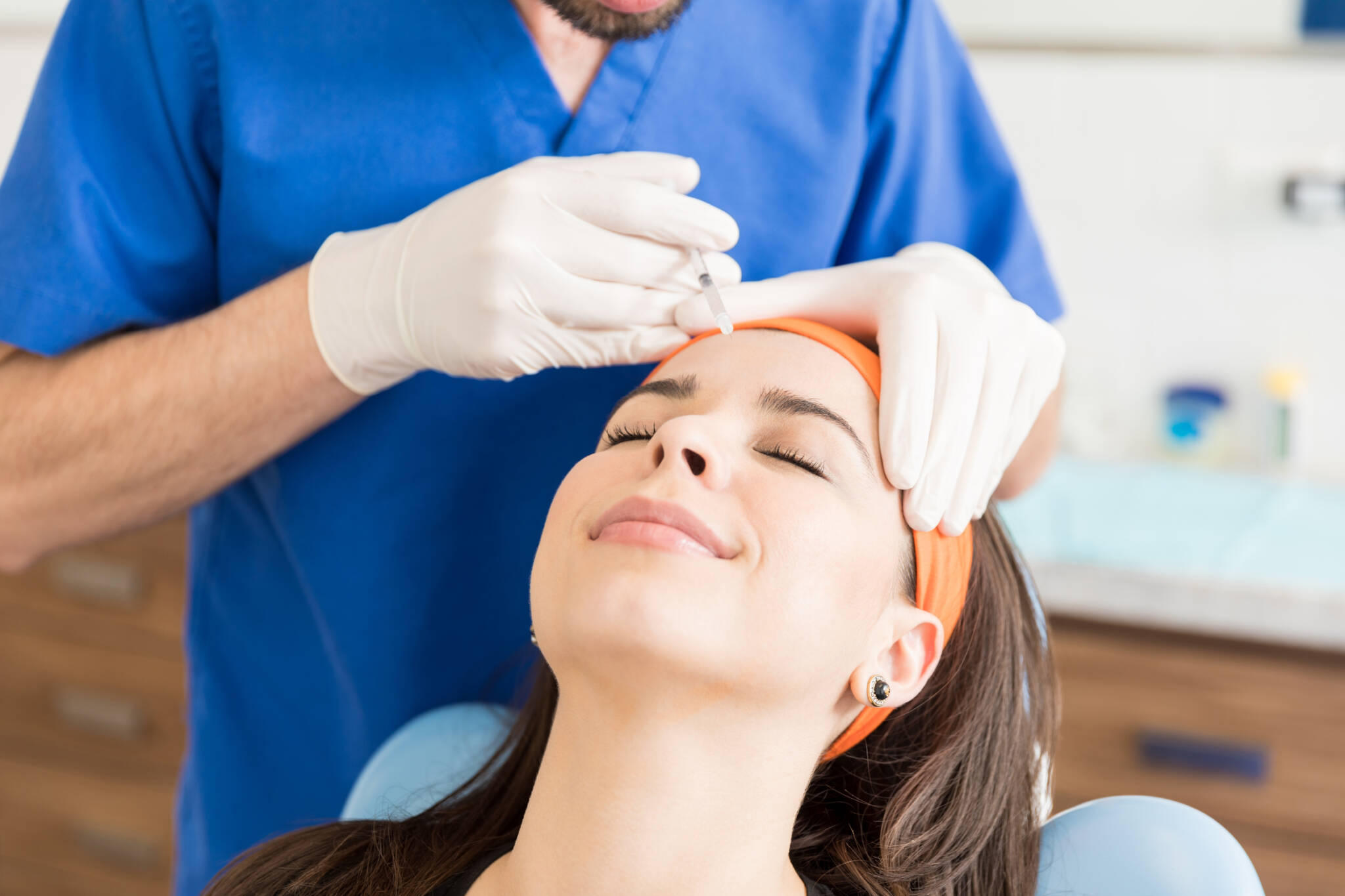 Woman receives a Baby Botox injection in her forehead to treat wrinkles.