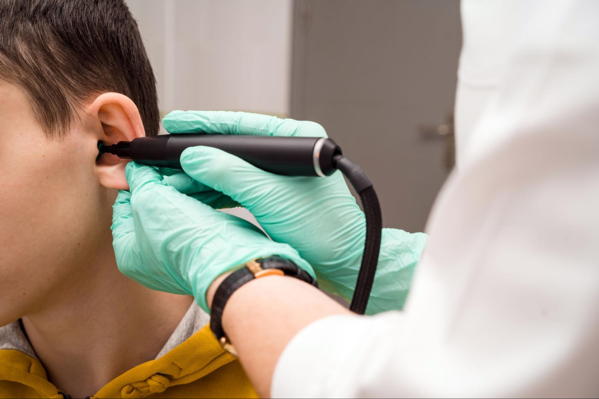 Doctor examining a patient’s ear during an otoplasty consultation