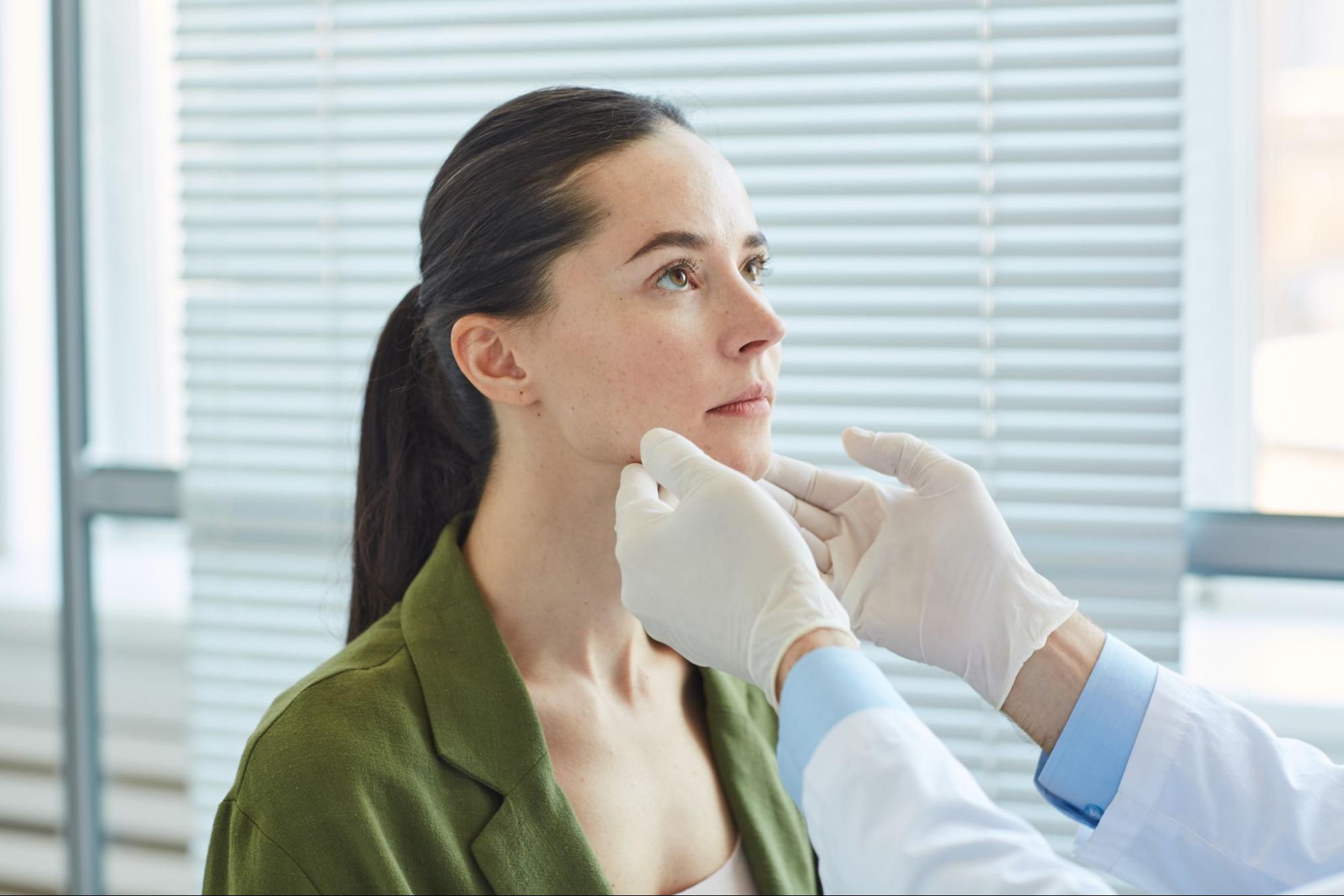Plastic surgeon evaluating a woman's chin and facial profile during a chin implant consultation.