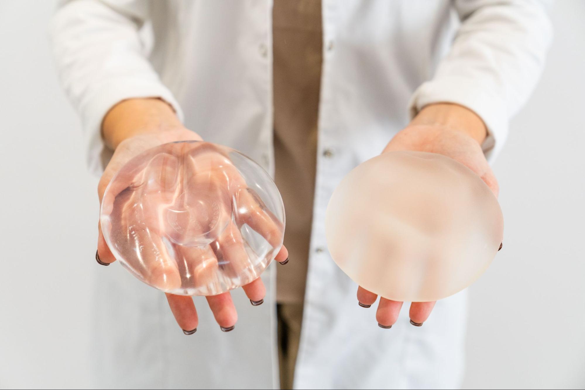 Plastic surgeon holding a breast implant and a silicone implant shell.